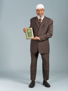 Dr. Zakir Naik, a prominent Islamic scholar, holding a book that symbolizes his dedication to spreading knowledge and understanding of Islamic teachings."